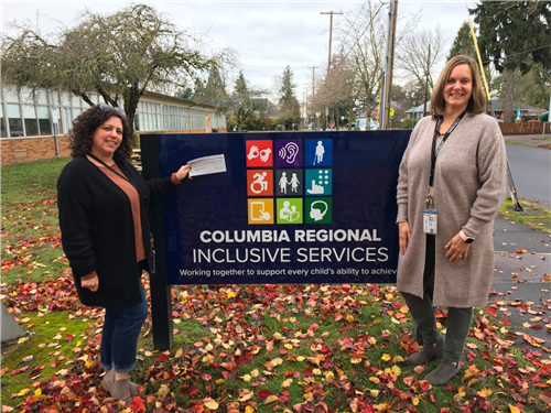 Alexis and Kristy standing in front of Columbia Regional Sign with check for grant to program